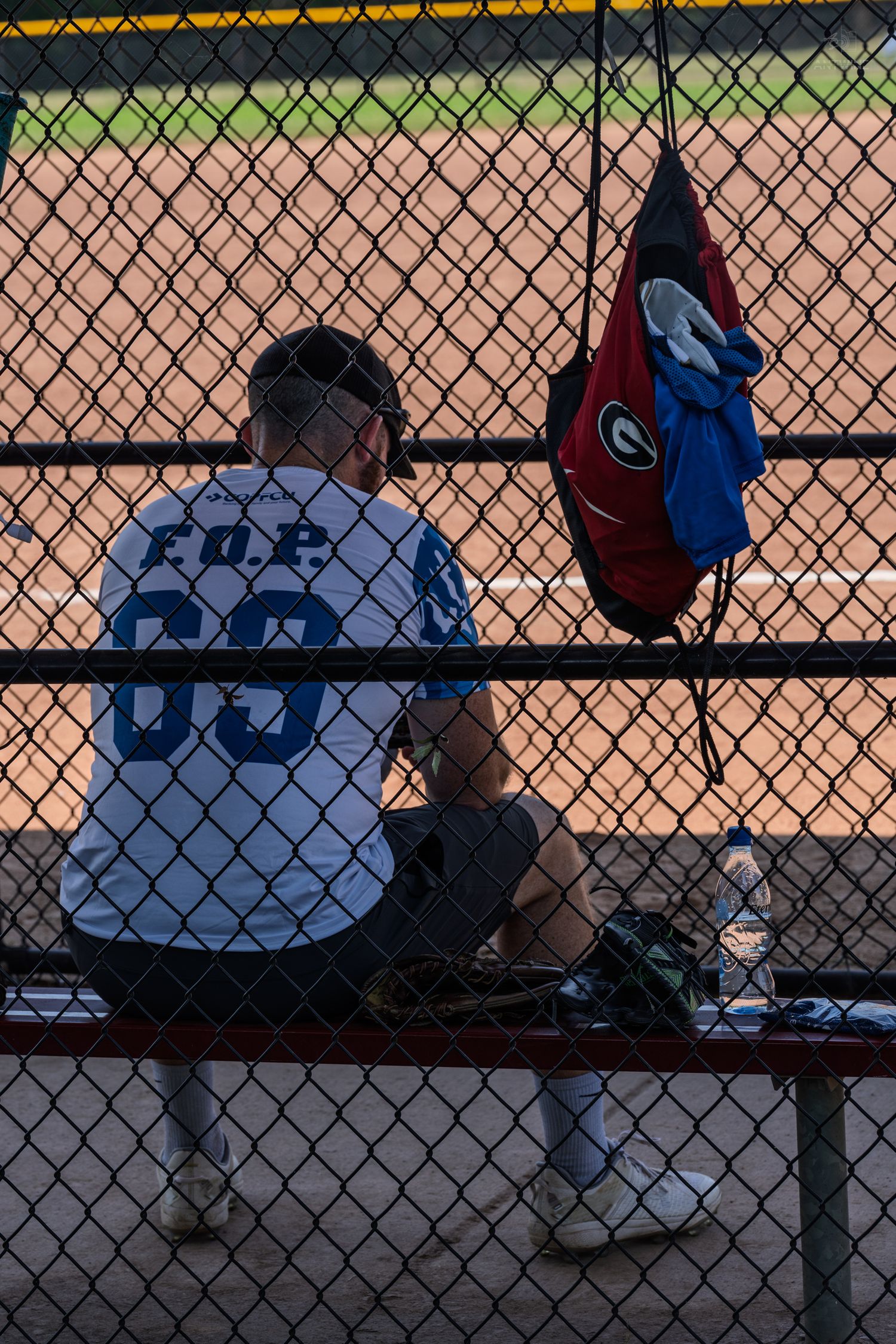 Softball player in FOE 69 jersey sitting on dugout bench near Georgia flag.