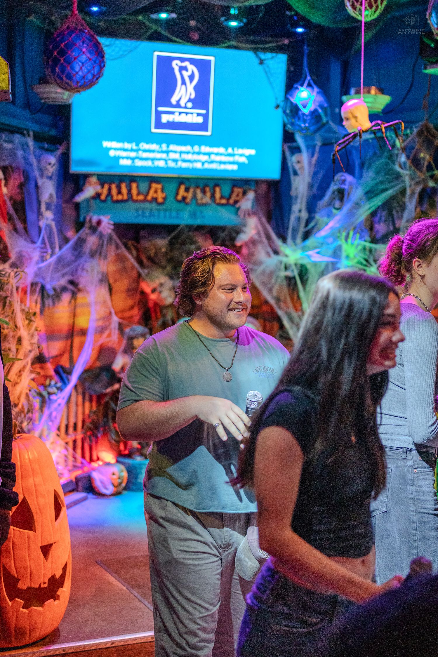 People enjoying a Halloween-themed party at Hula Hula Seattle with spooky decorations and jack-o-lanterns.