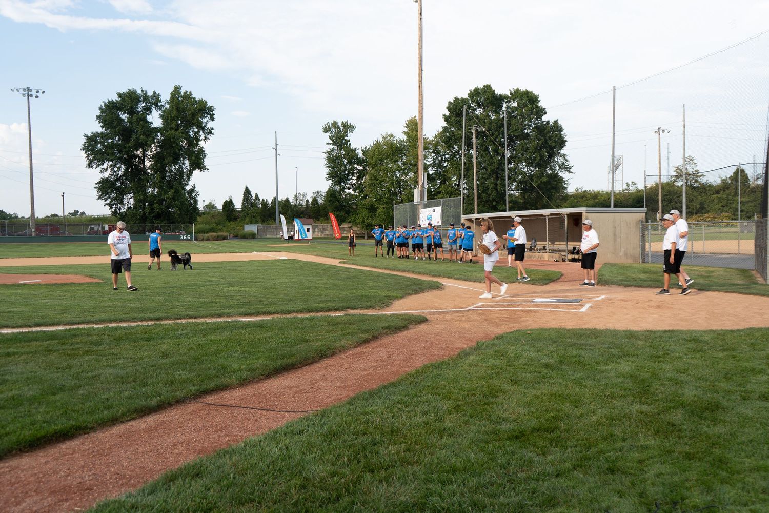 Players warming up on a baseball diamond during a sunny outdoor game at a well-maintained community baseball field.