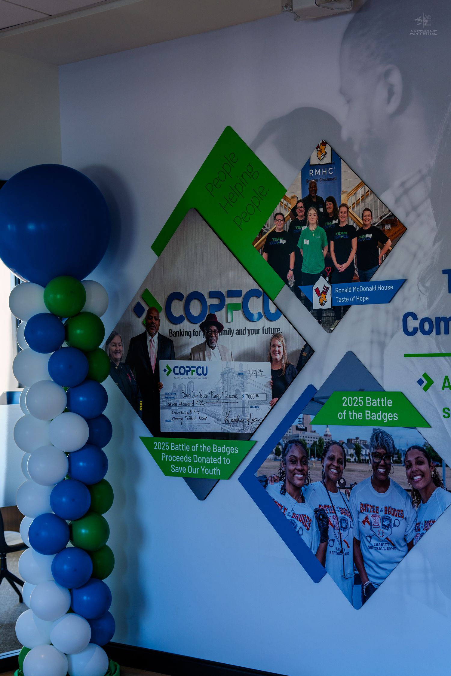COPFCU credit union branded display wall with diamond shapes, balloon column in blue and green, featuring Battle of the Badges event.