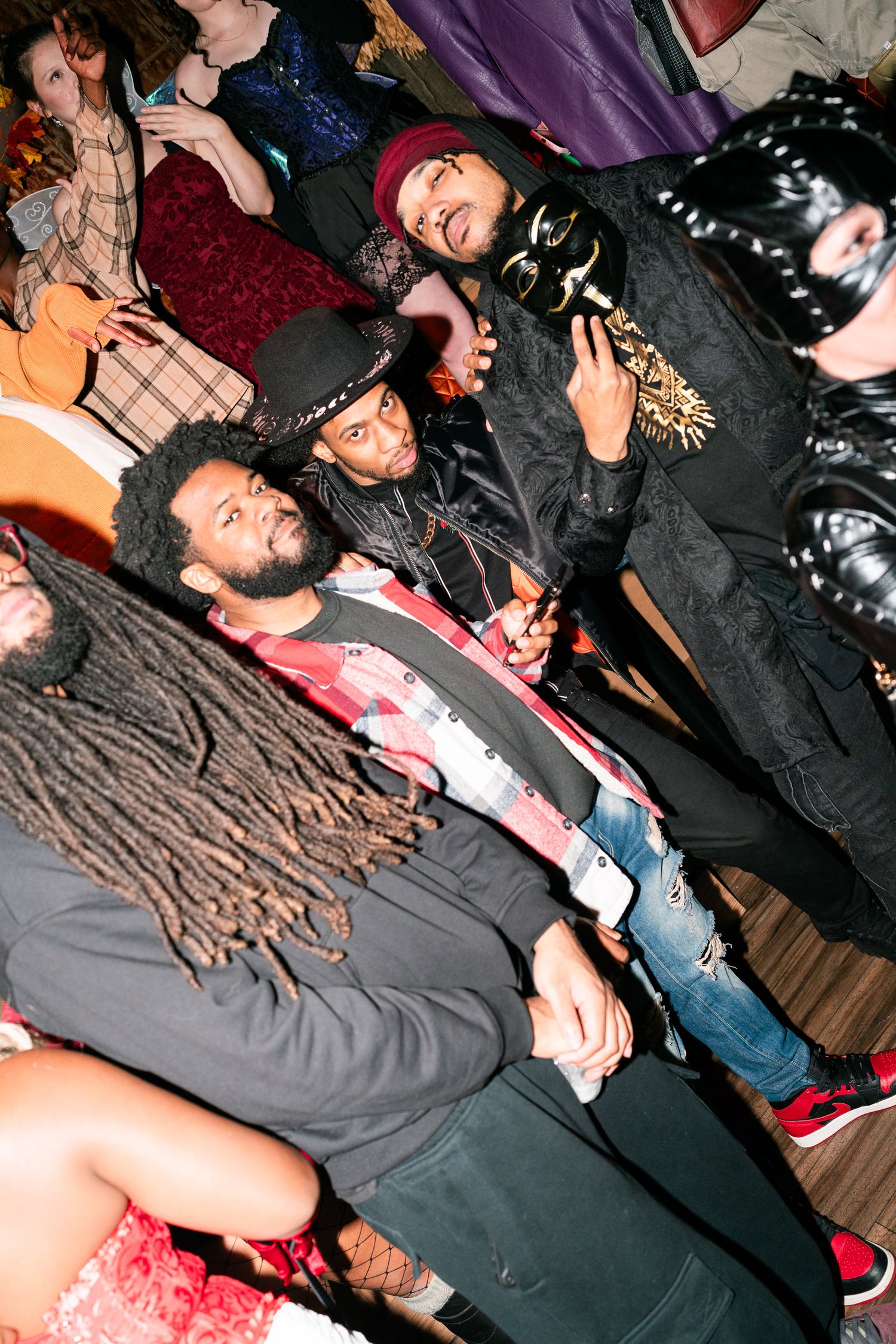 Group of men in Halloween costumes posing together at a lively nightclub party event.