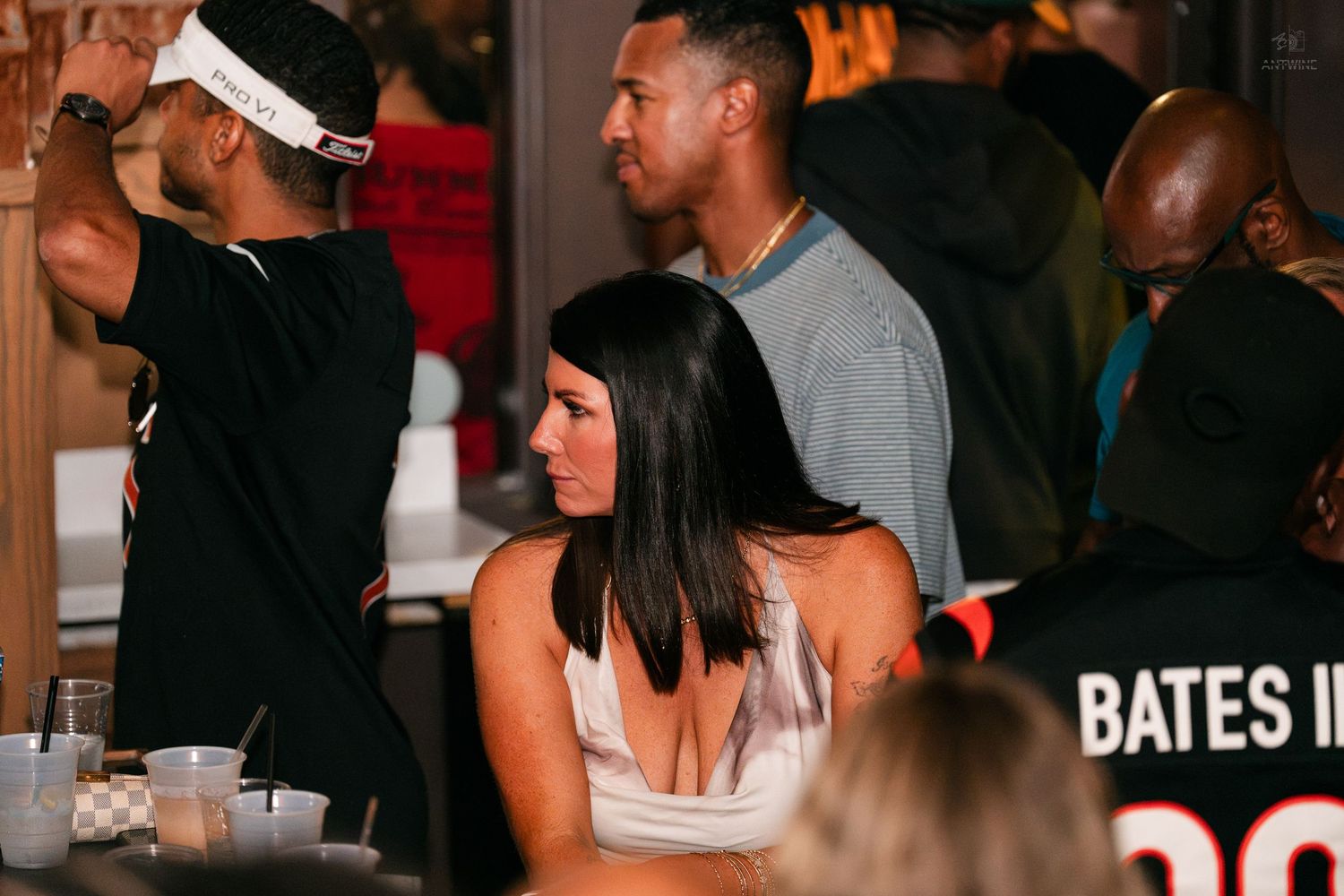 Man and woman standing together in a crowded bar venue with Bates jersey visible.