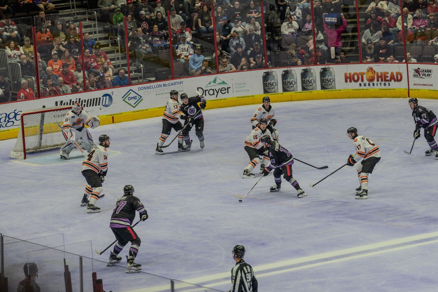 Hockey players battle for the puck near the goal during an intense professional indoor ice hockey game.