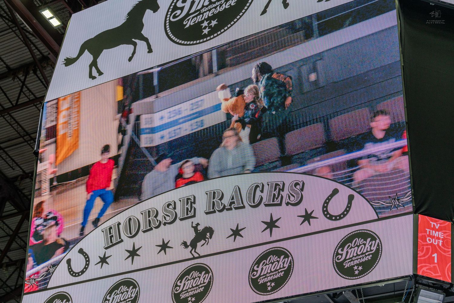 Arena scoreboard displays Horse Races entertainment promotion during an indoor hockey game event.