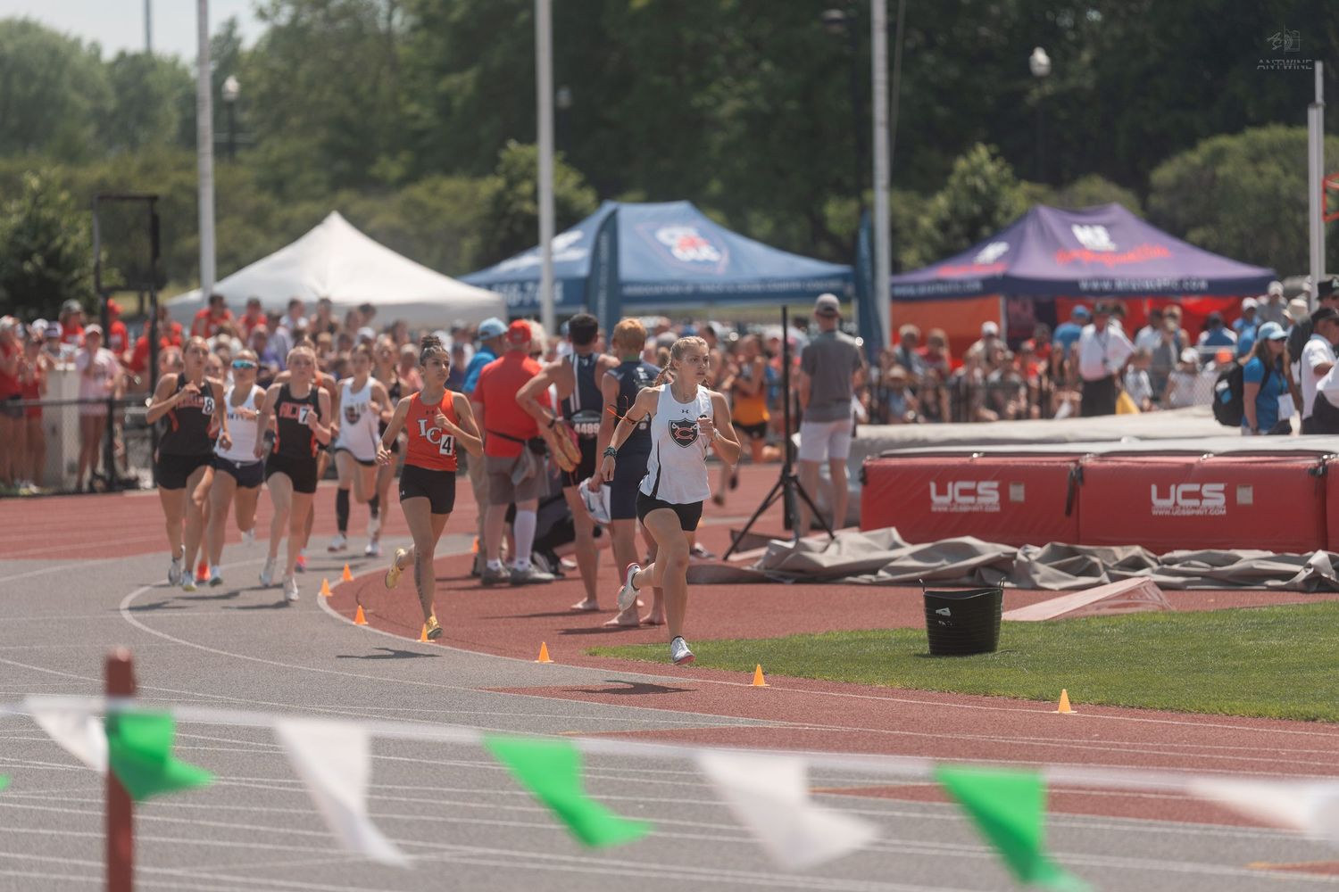 Track athletes lined up on red track at outdoor collegiate track and field competition.