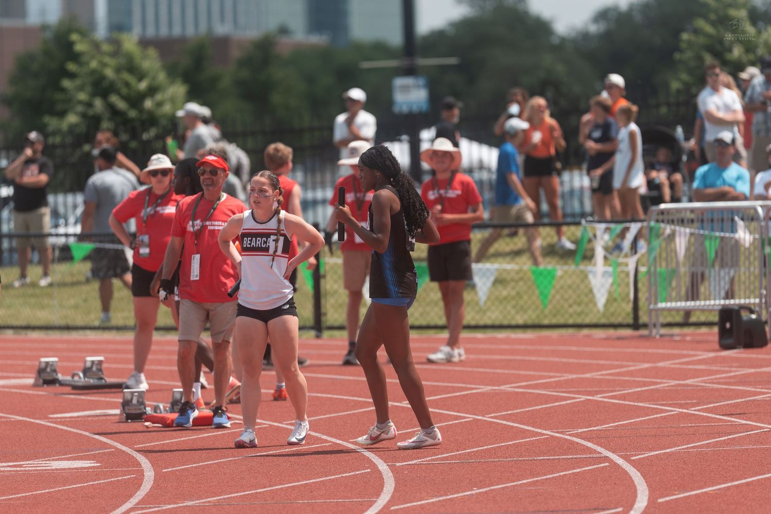 Female track athletes rest and socialize on the red track after competing at an OHSAA championship meet.