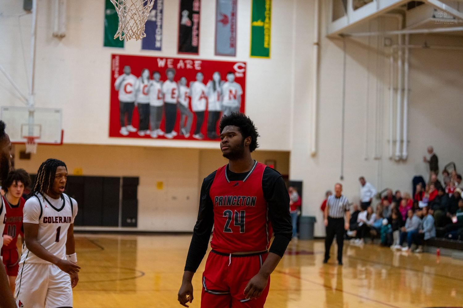 Princeton basketball player #20 in red uniform stands on court during high school game at Coleman gym.