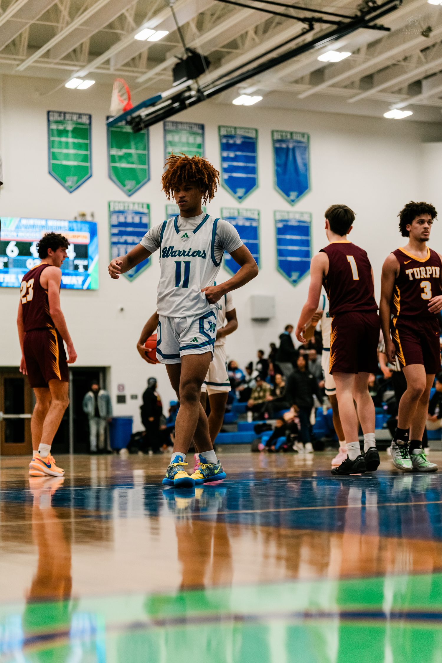 High school basketball player in white Warriors jersey number 11 dribbles ball during game against Turpin.