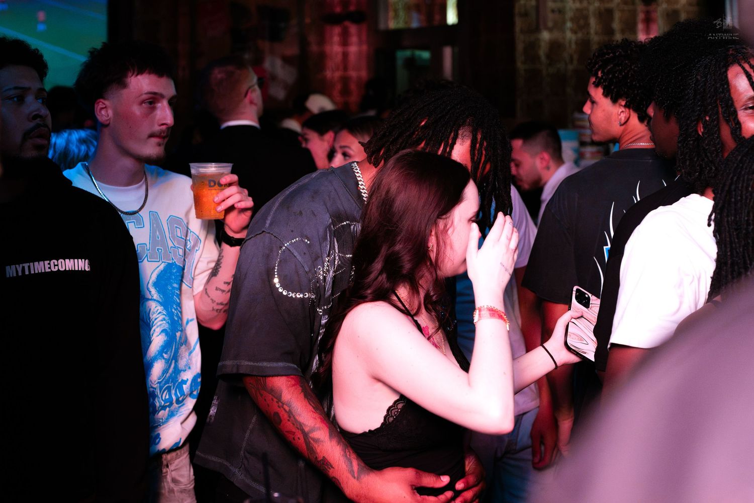 Group of young adults mingling and drinking at a busy bar event.