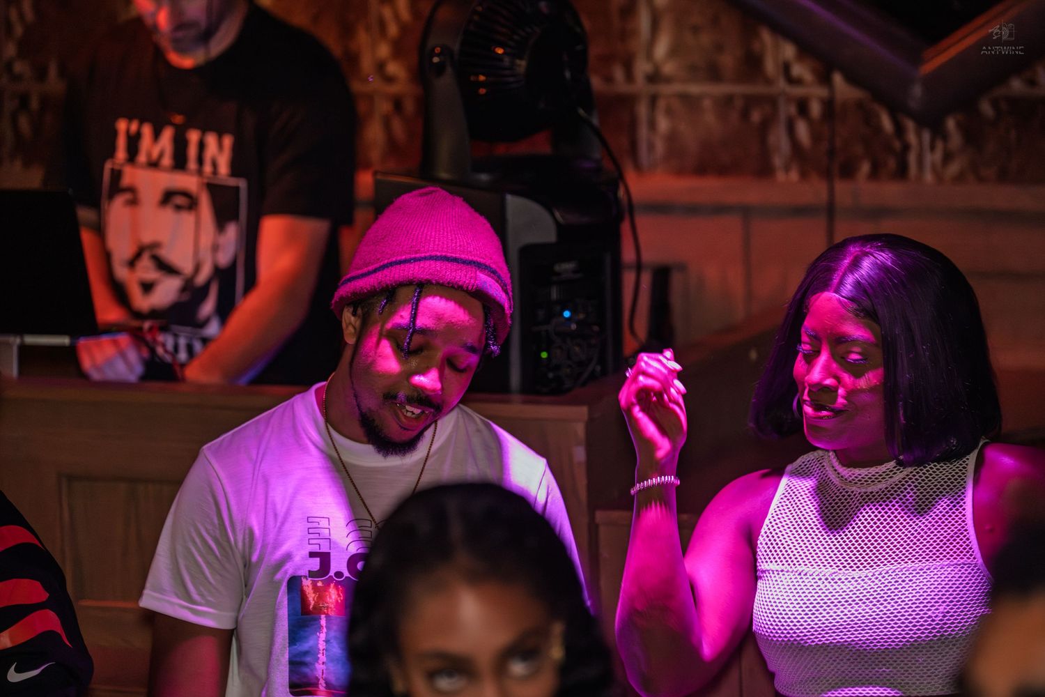Young couple enjoying music under purple lights at a lively nightclub event.