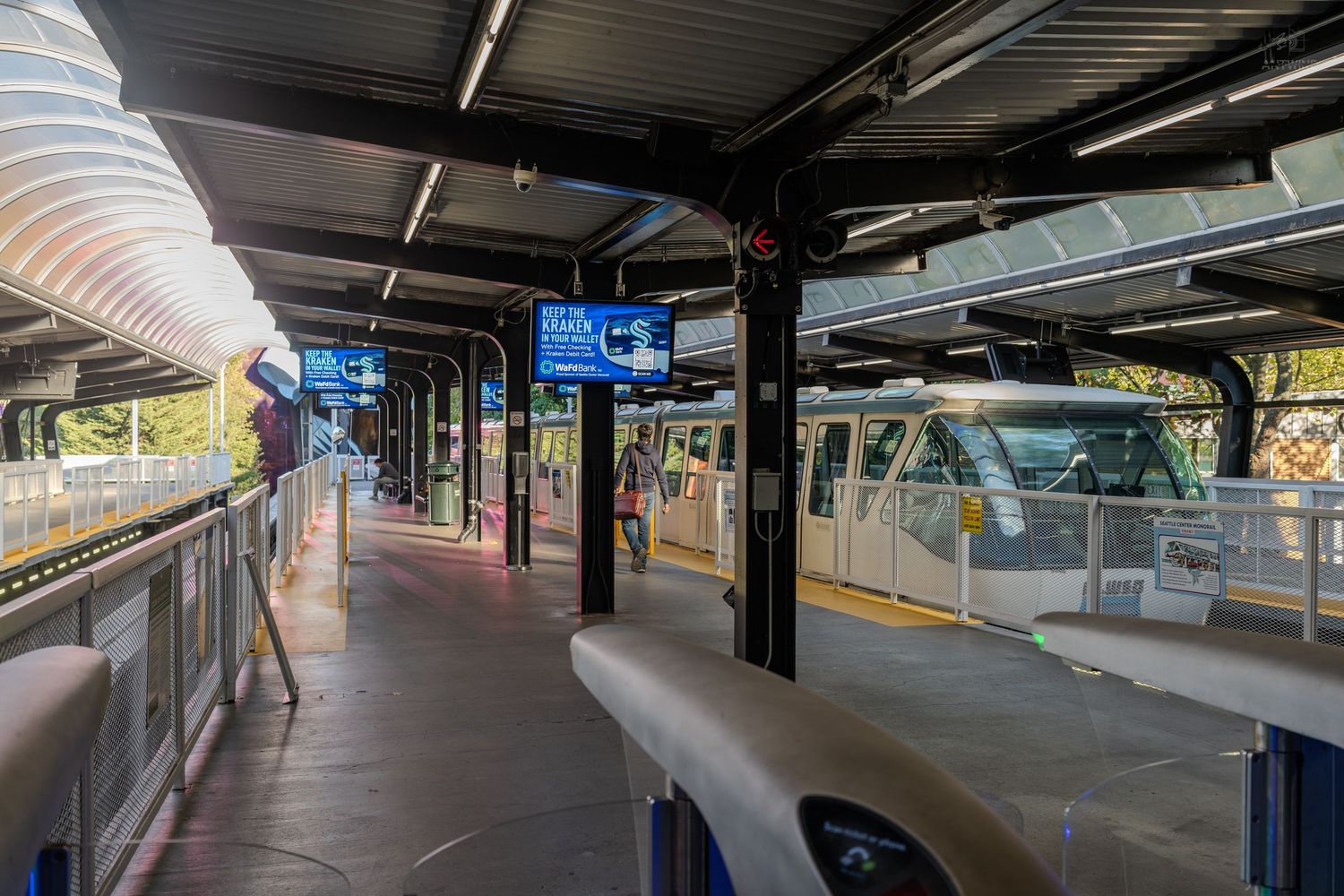 Seattle monorail station platform with train and digital display signs.