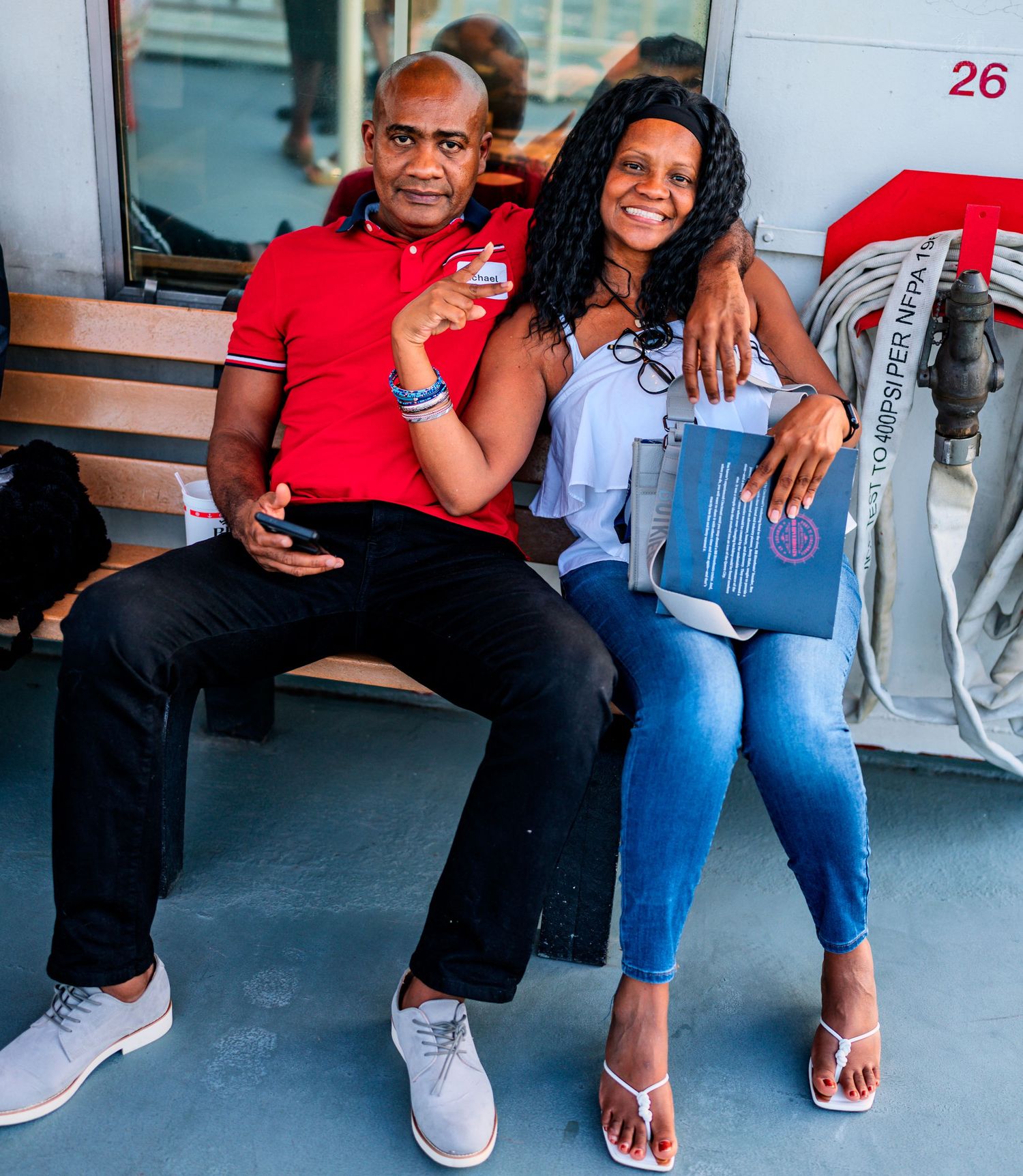 Couple sitting together smiling on a riverboat deck during a daytime cruise.