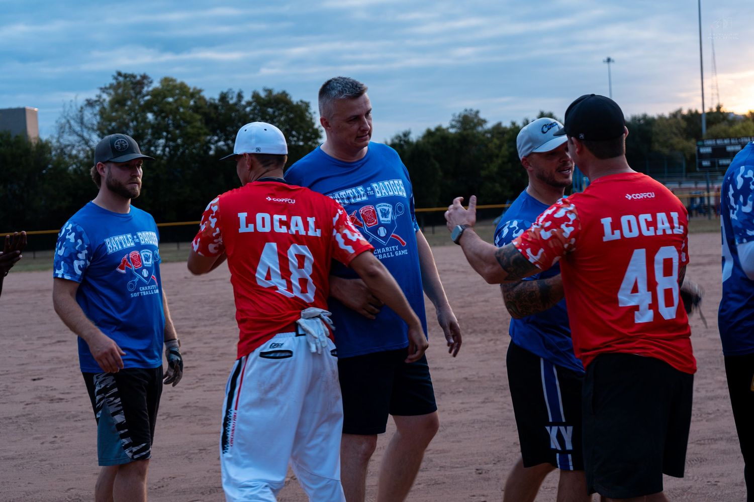Softball players in red Local 48 jerseys congratulate each other after an evening game.
