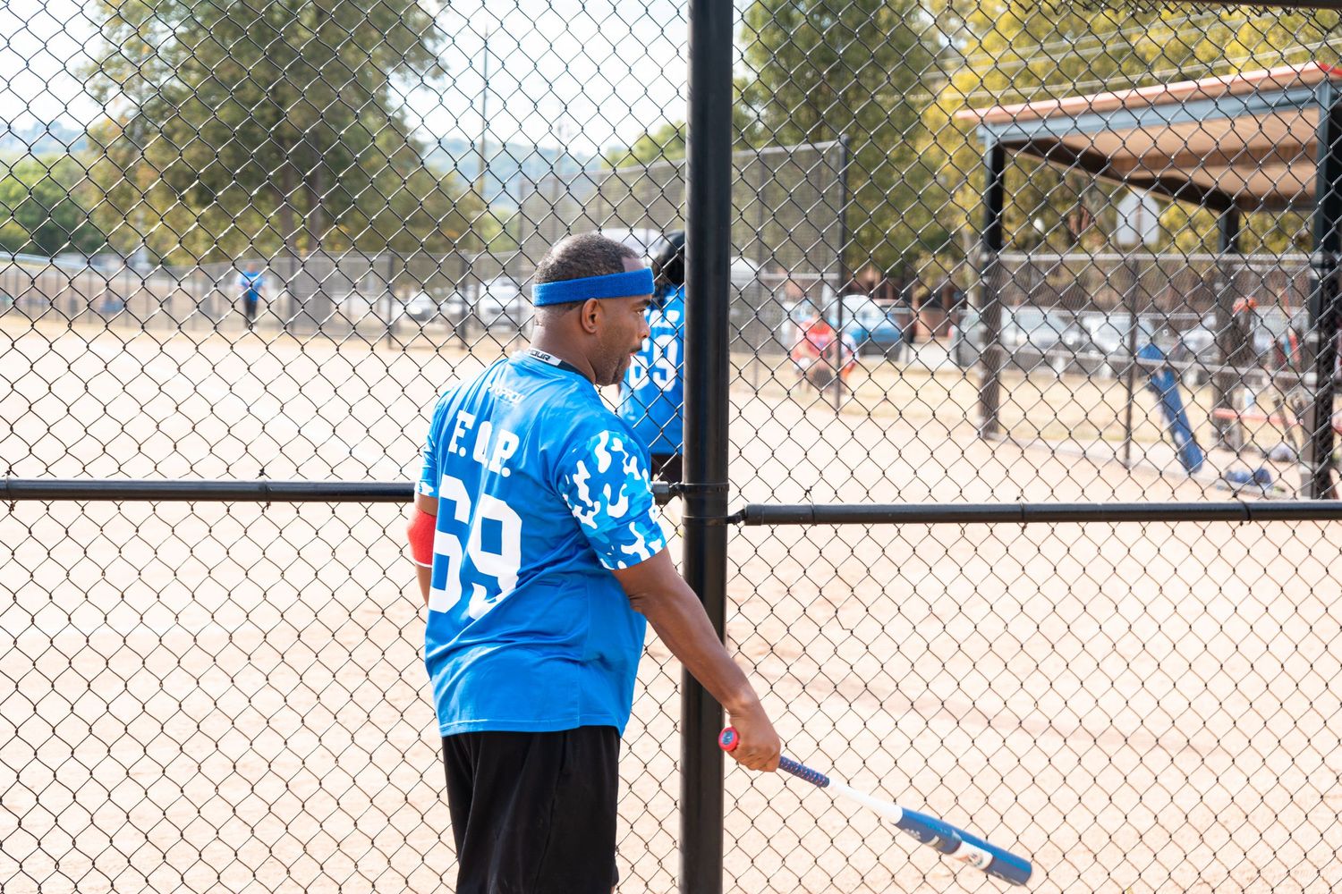 A softball player wearing number 69 blue jersey holds a bat on the field.
