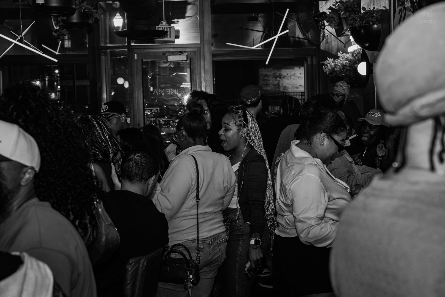 Crowd of people socializing inside a busy bar or nightclub, black and white photo.