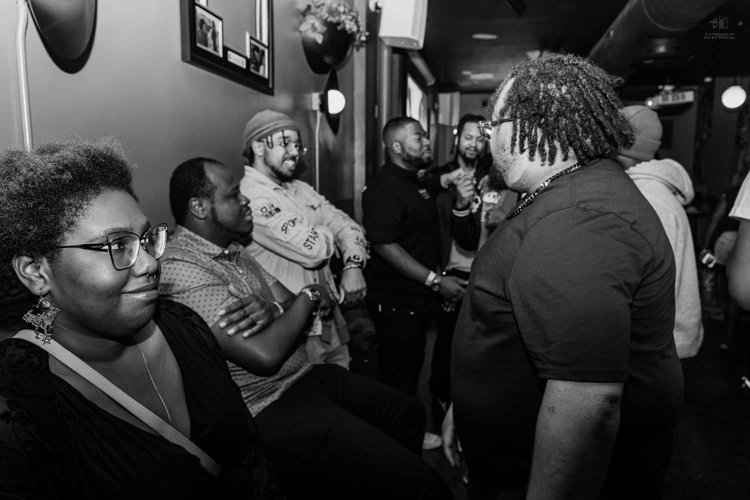 Black and white photo of a diverse group of people socializing at an indoor gathering or party event.