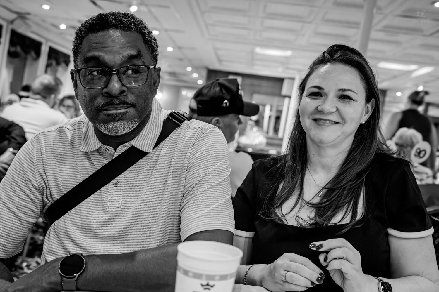 A man and woman smile together at a table in a black and white event photo.