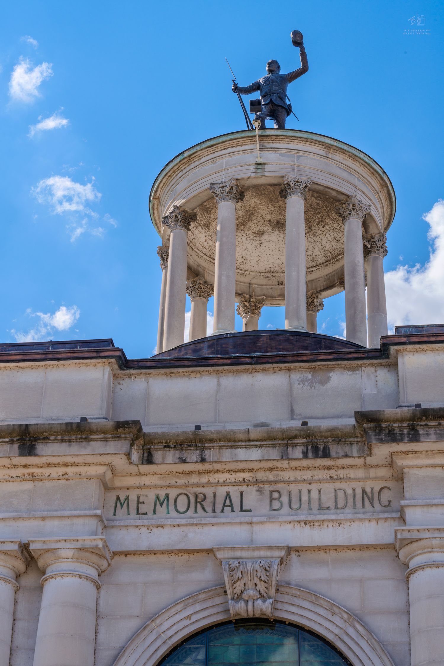 Historic Memorial Building facade with classical rotunda, Corinthian columns, and bronze soldier statue against blue sky.