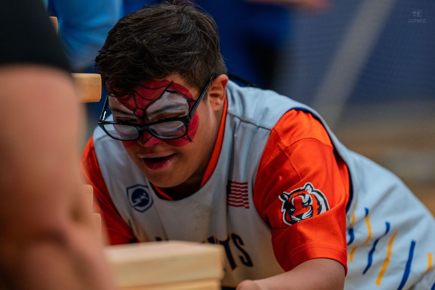 Young athlete wearing a Spiderman face mask and sports jersey competes in an adaptive sports event.