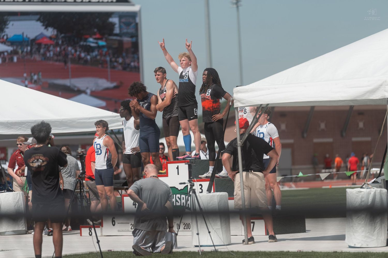 Athletes celebrate on the winners podium at an outdoor track and field championship competition.