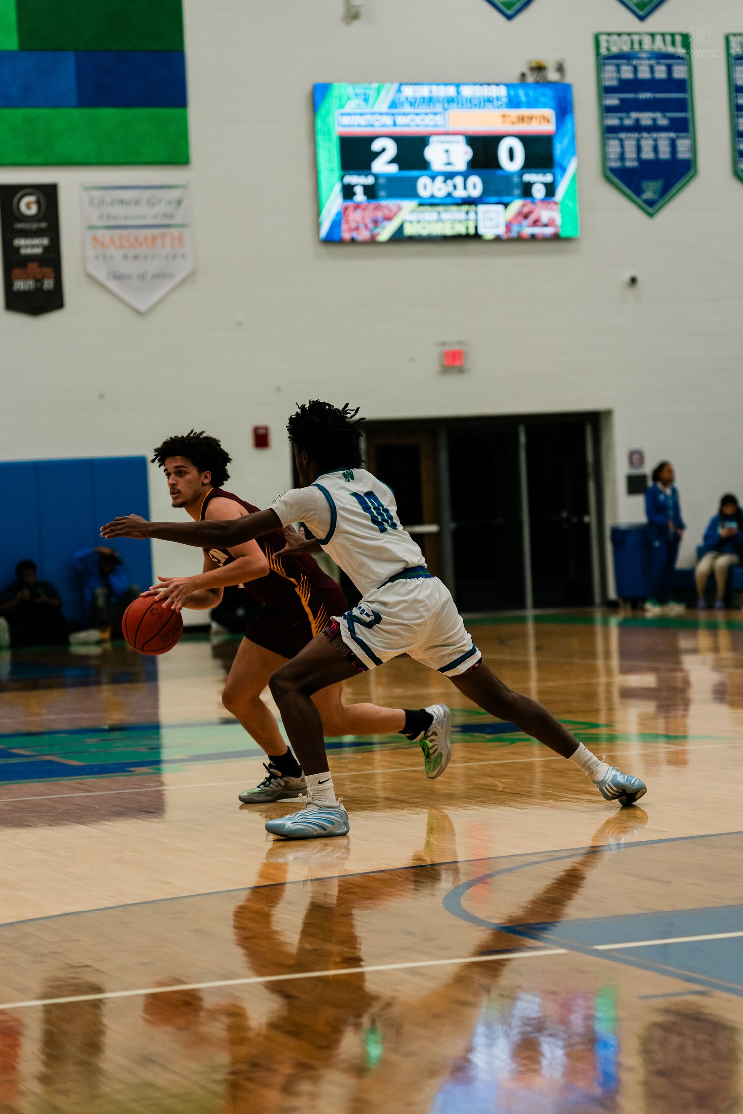 Turpin basketball player drives to the basket while being defended during a high school game with scoreboard visible.