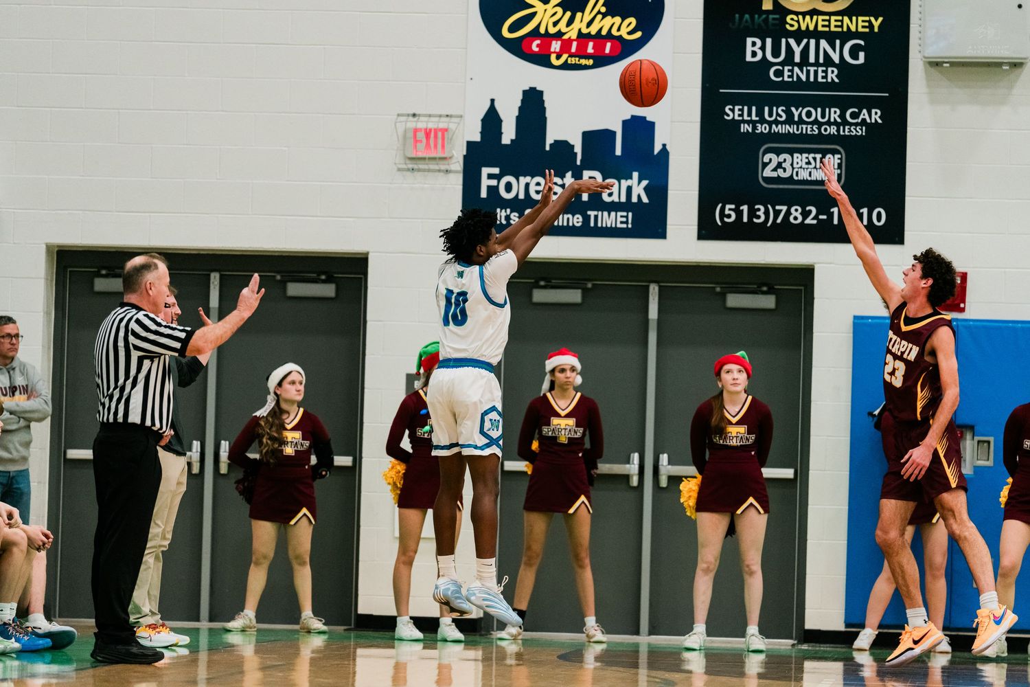 Winton Woods player #16 shoots over Turpin defenders near baseline during high school basketball game.