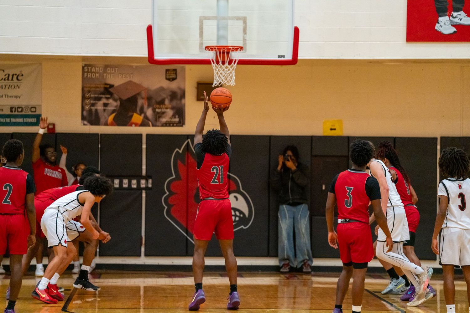 A basketball player in red attempts a layup during a competitive high school basketball game.