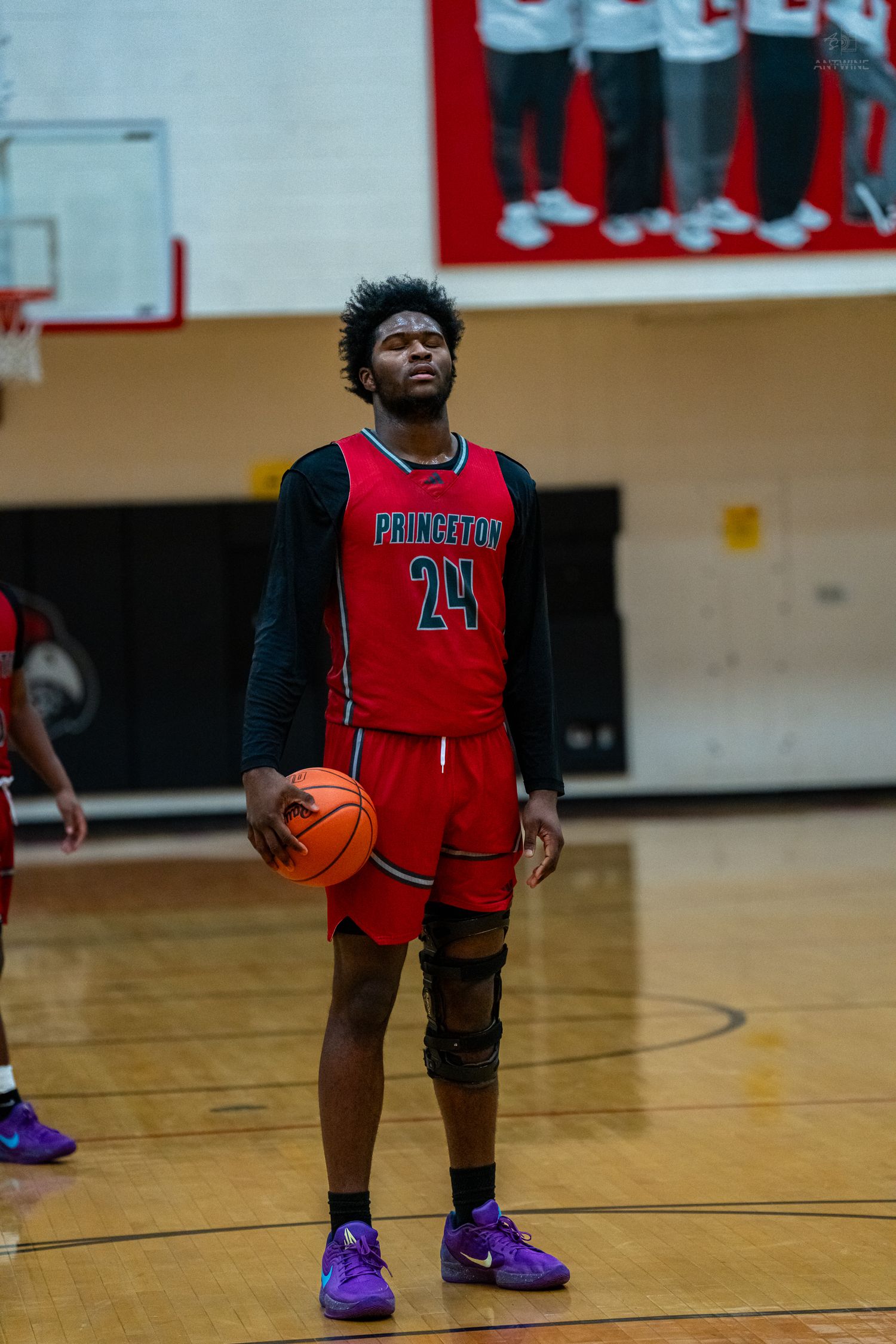 Princeton High School basketball player number 24 stands at the free throw line holding a basketball.