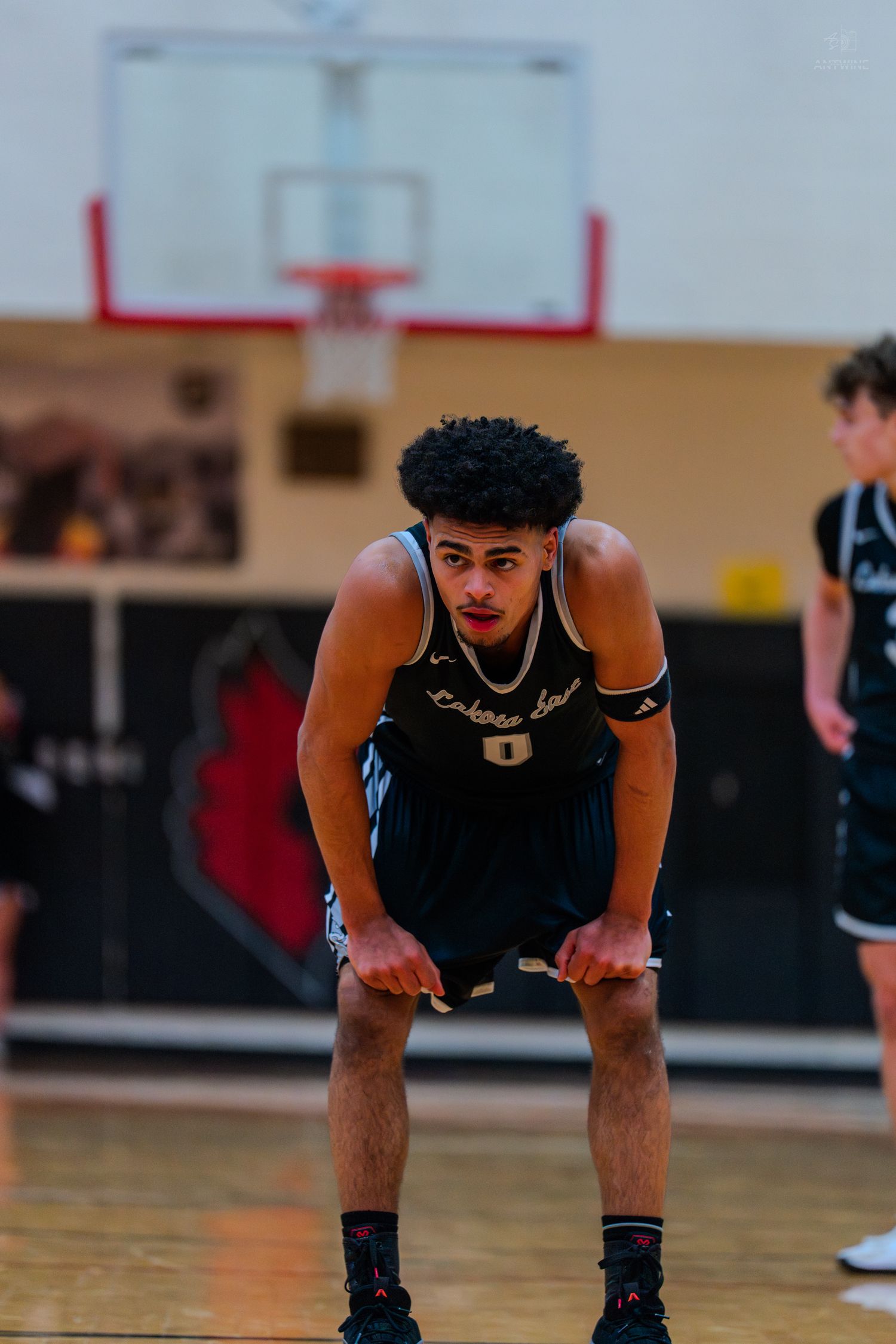 Lakota East basketball player #0 bends over catching breath during game.
