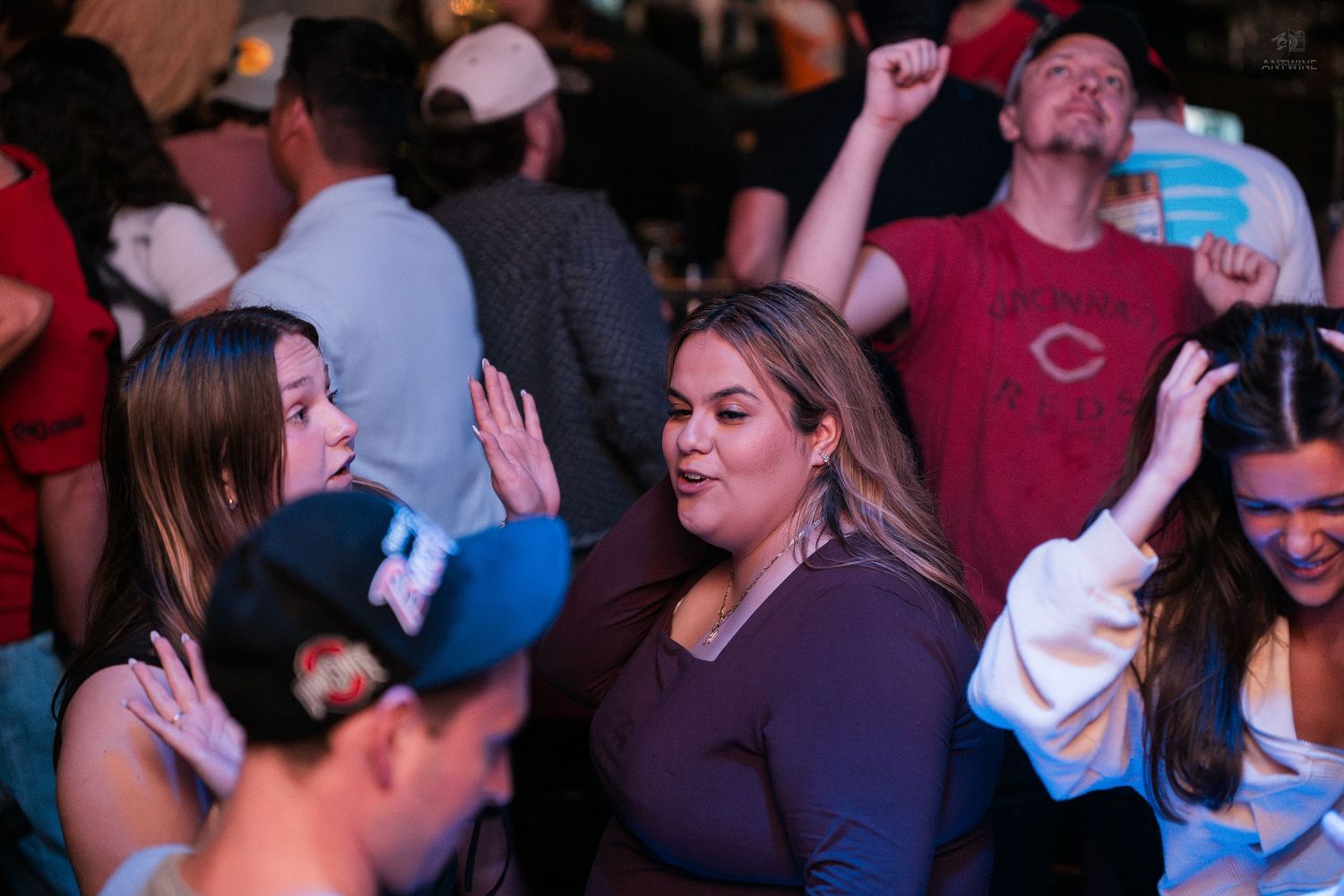 Group of friends dancing and having fun at a crowded indoor bar nightlife event.