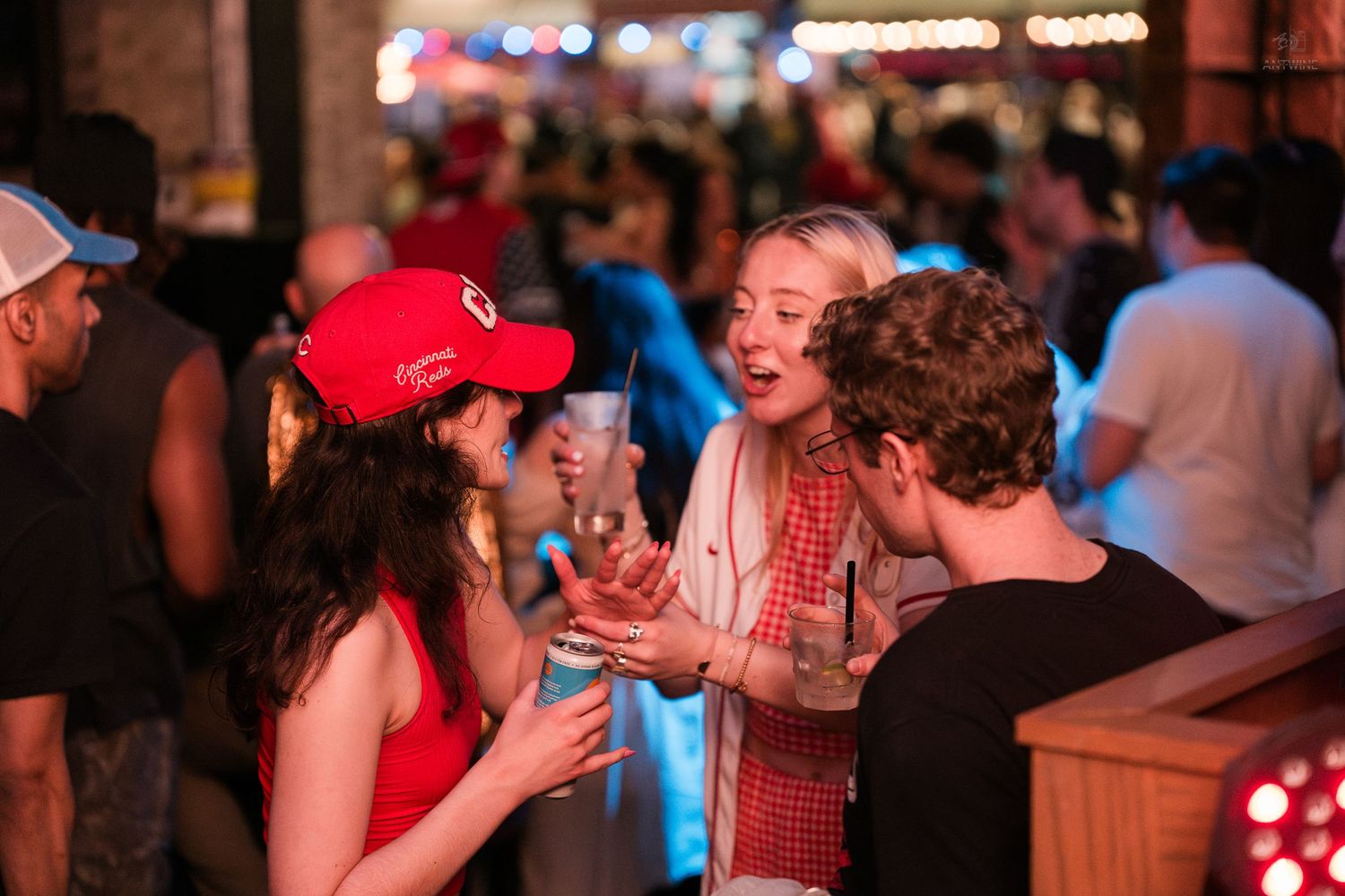 Group of friends laughing and holding cocktails at a vibrant nightclub gathering.