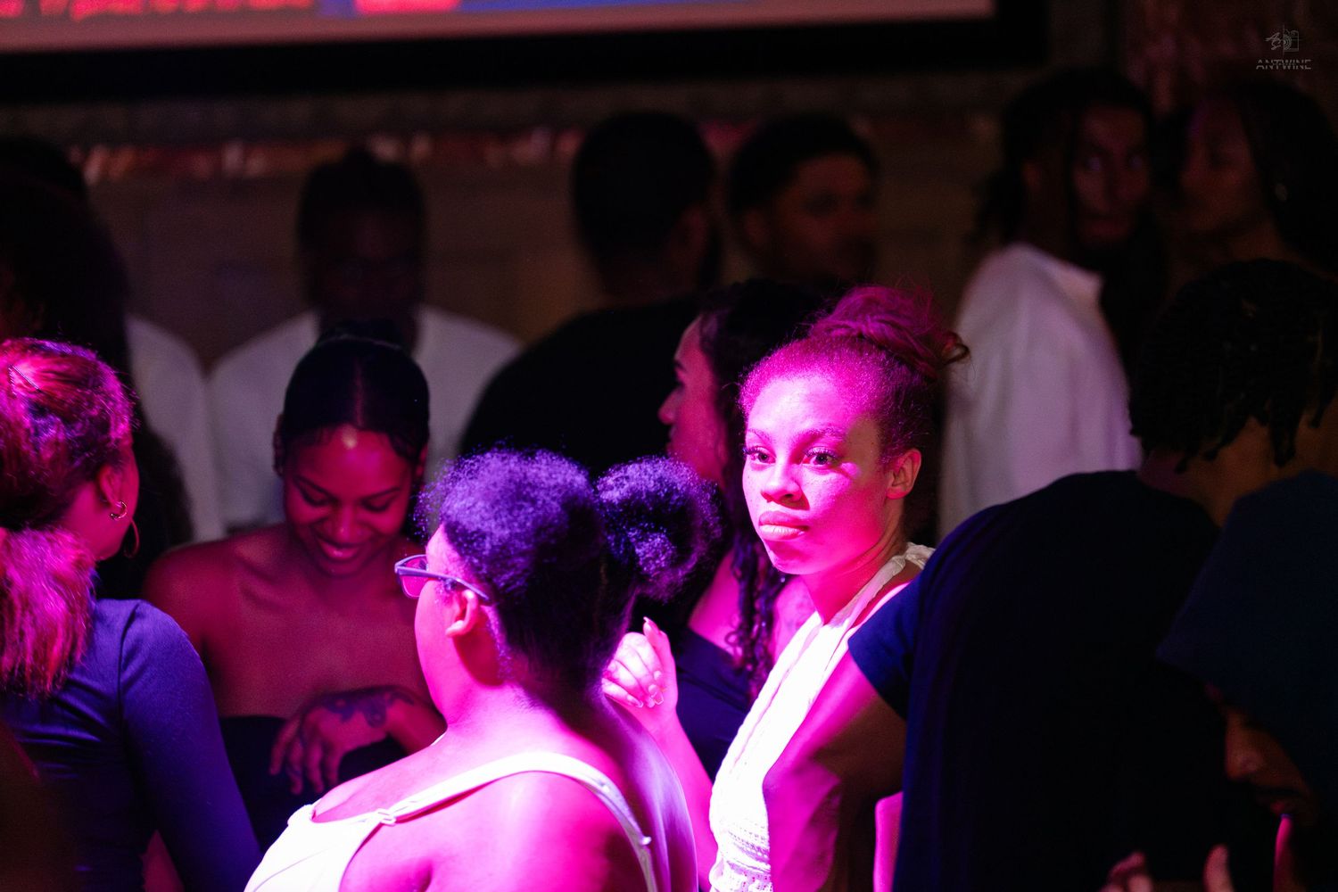 Group of people socializing under purple lighting at a nightclub event.