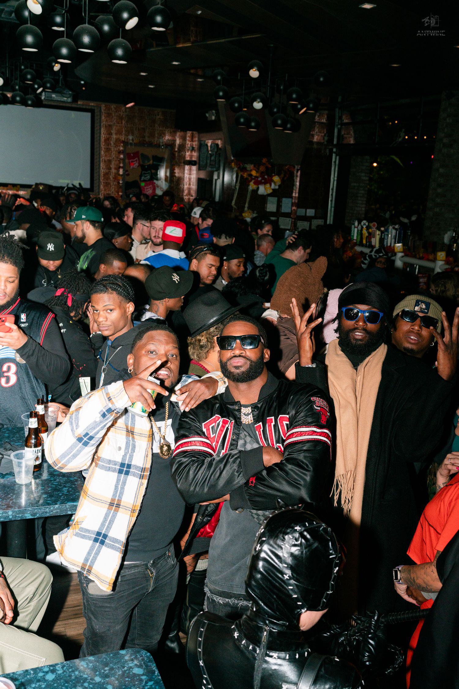 Group of men posing and celebrating at a crowded nightclub event.