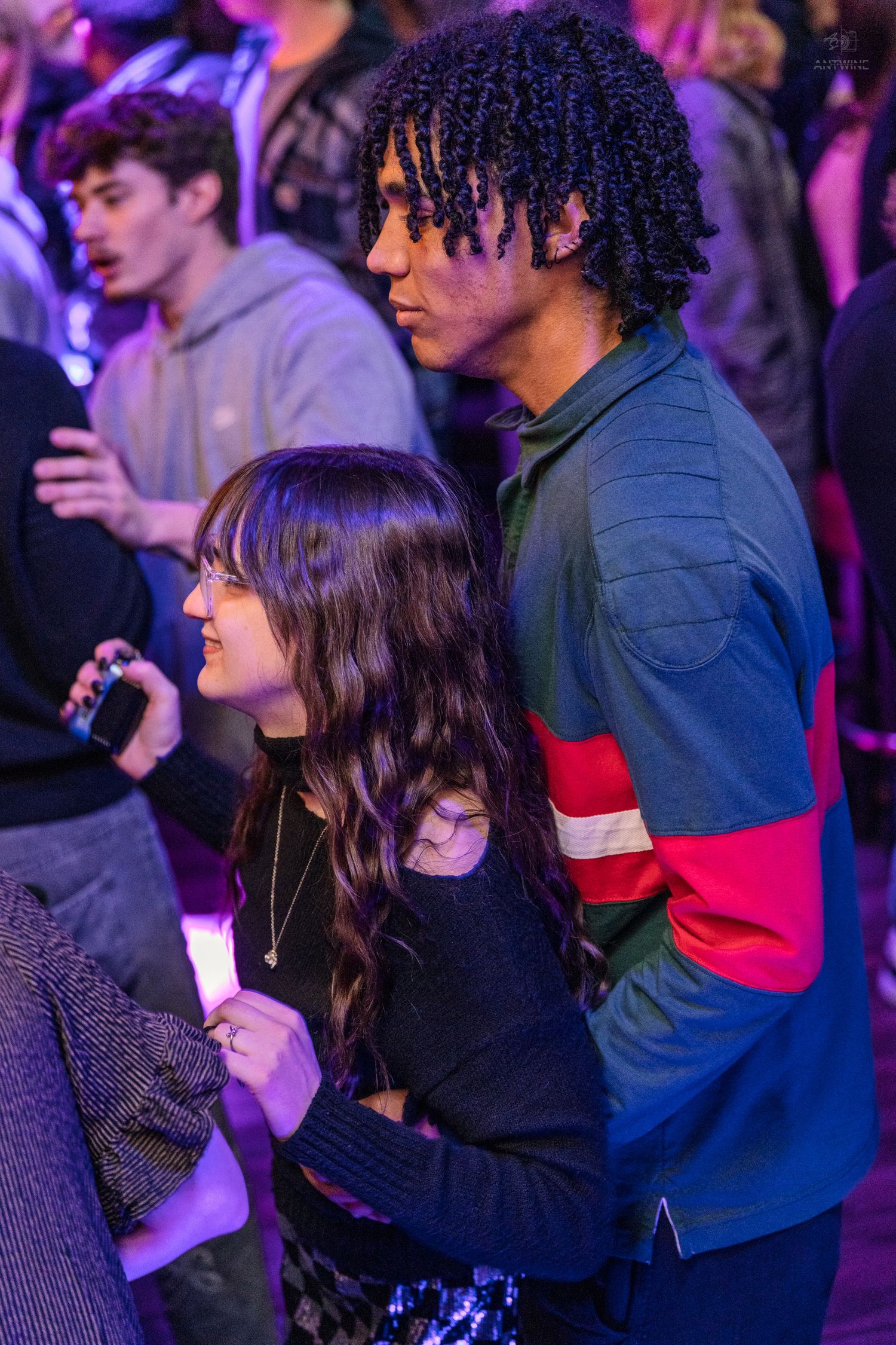 Young couple standing close together at a lively indoor party event.