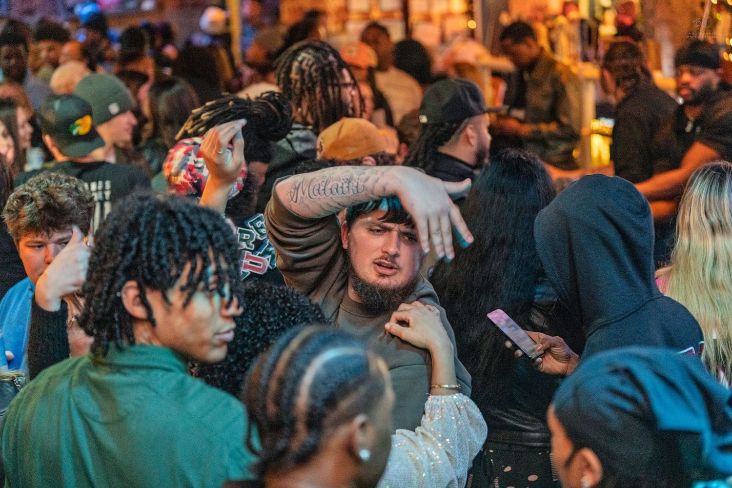 A diverse crowd of young people socialize and mingle at a lively outdoor nighttime event.