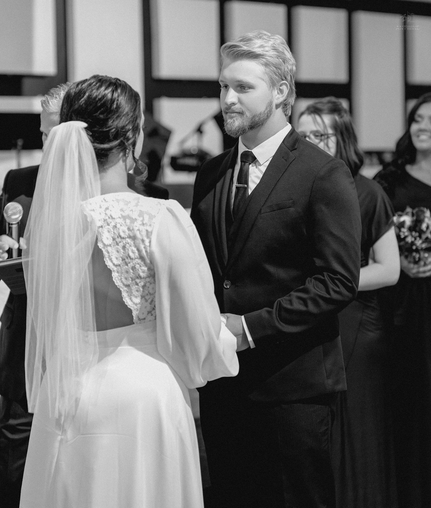 Black and white photo of a bride and groom exchanging vows at their wedding ceremony.