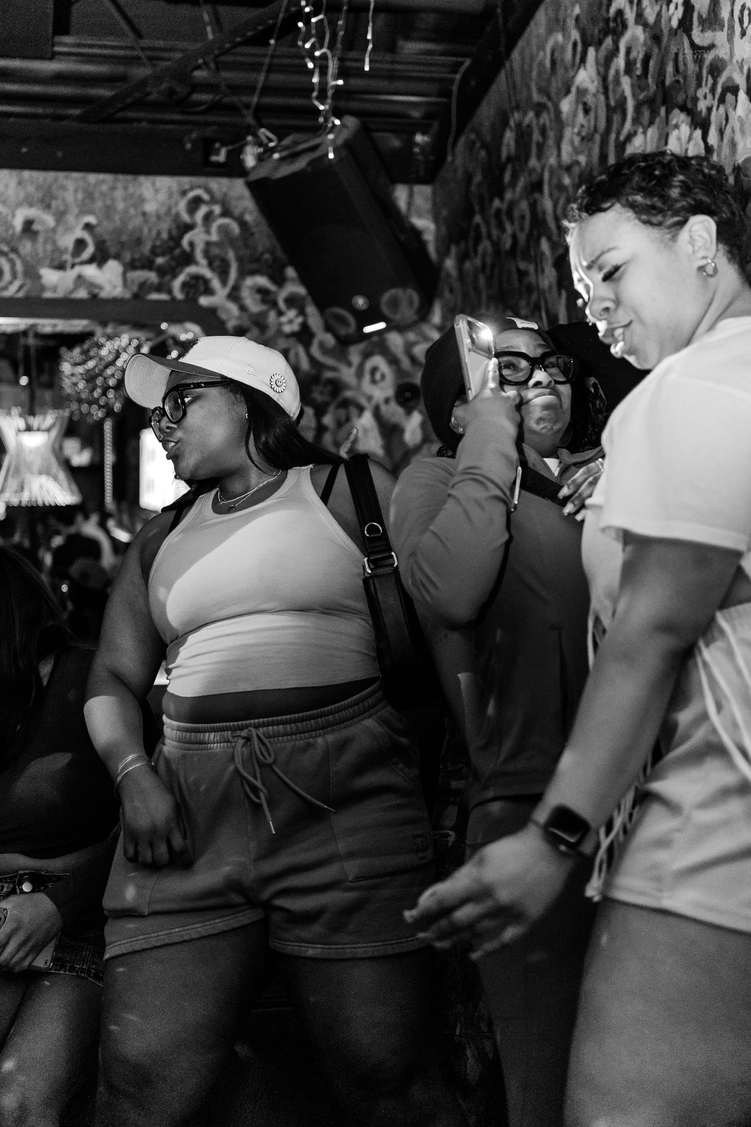 Group of people dancing and recording video at a lively indoor nightclub party.