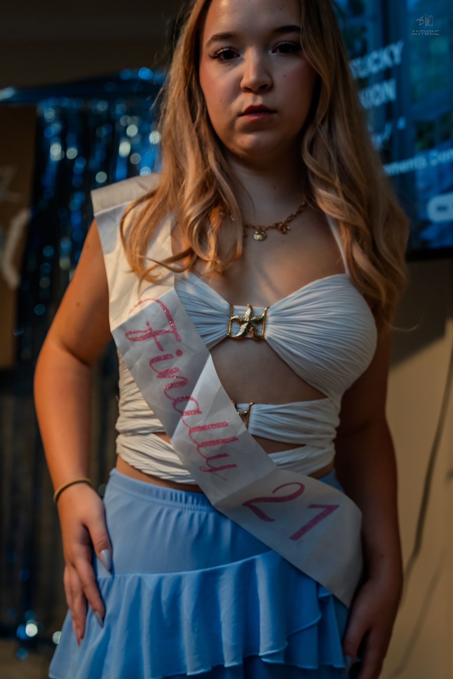 Birthday girl wearing Finally 21 sash in white crop top and blue ruffle skirt at her party.