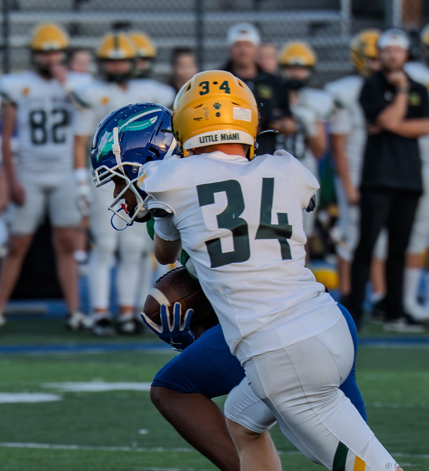 Little Miami player number 34 catches a pass while being defended during a high school football game.