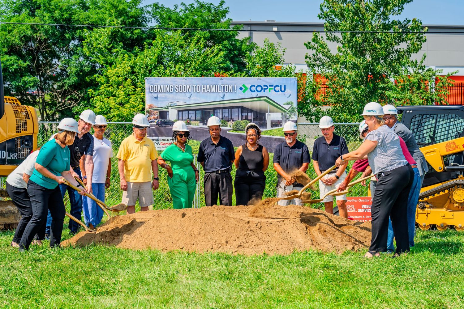 Large group in hard hats celebrating COPFCU groundbreaking ceremony with golden shovels in Hamilton.
