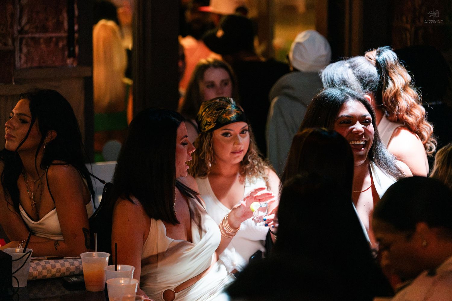 Group of women laughing and chatting together at a dimly lit nightclub event.