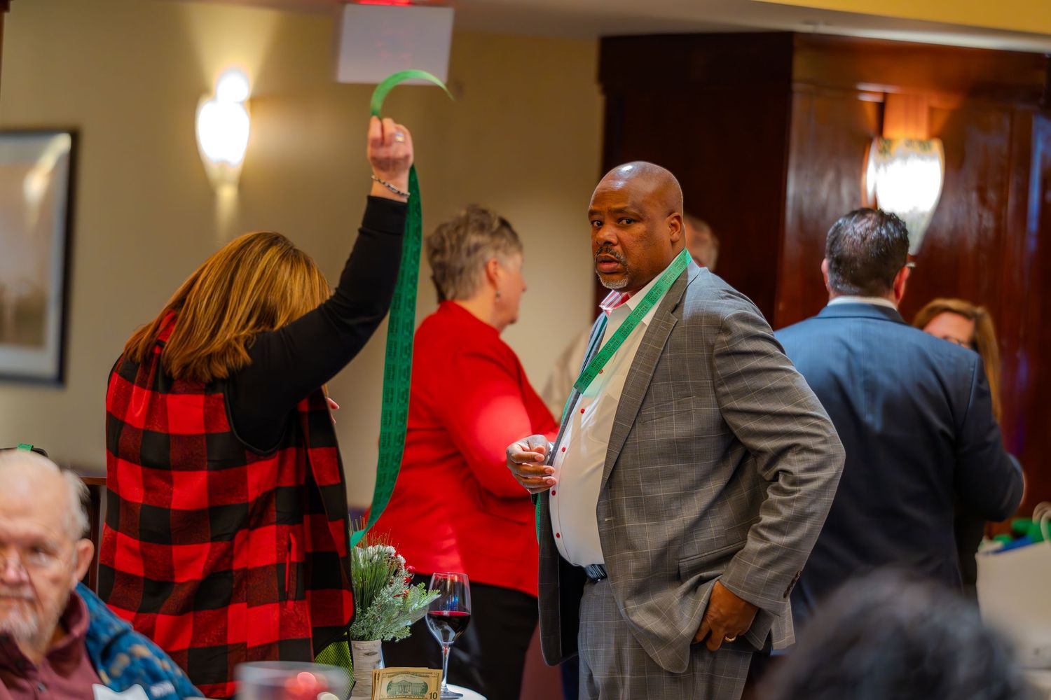 People mingling at a festive holiday party in formal attire with Christmas decorations.