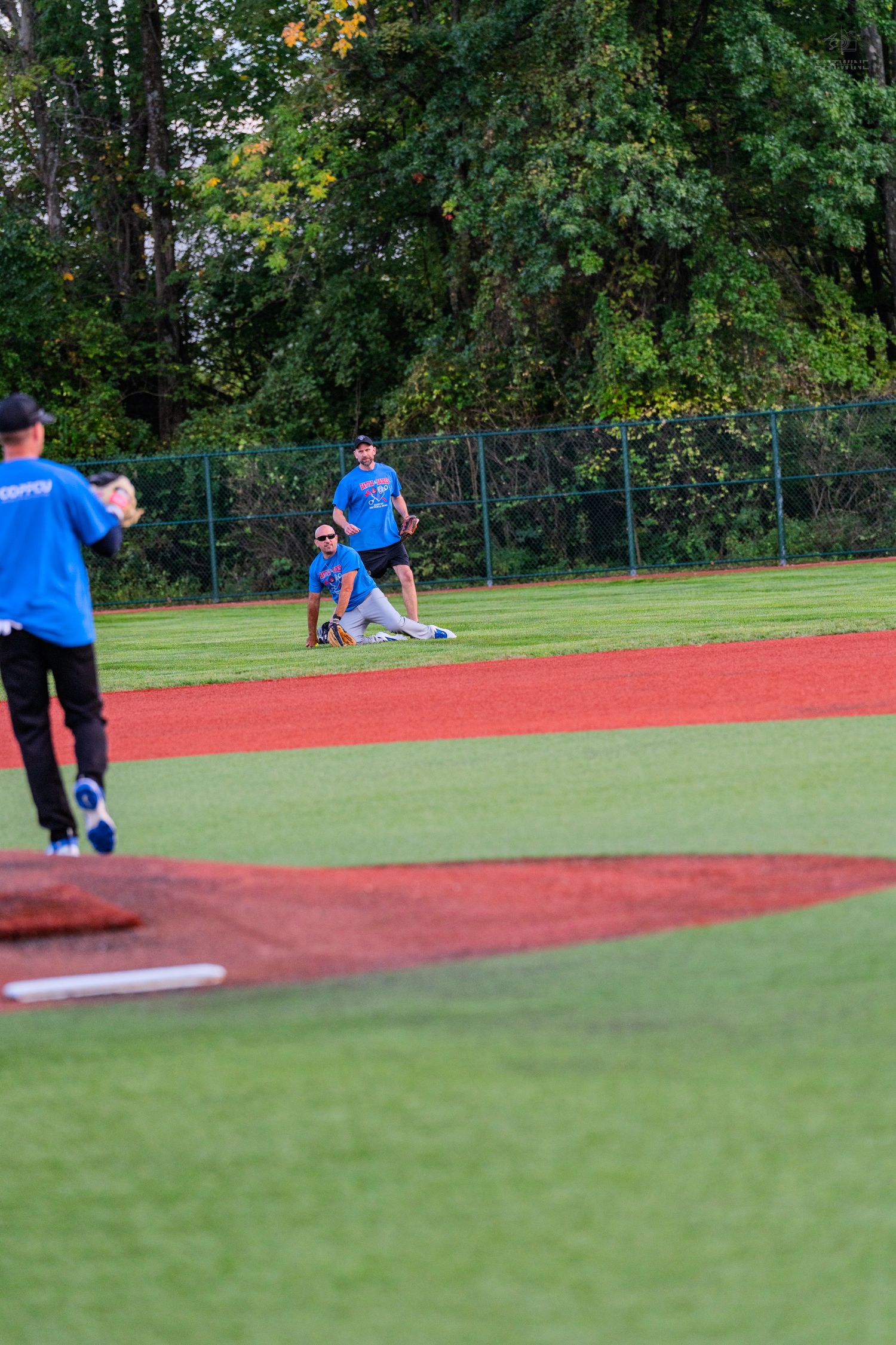 Baseball players in blue uniforms field a play near second base on a lush green and red diamond.