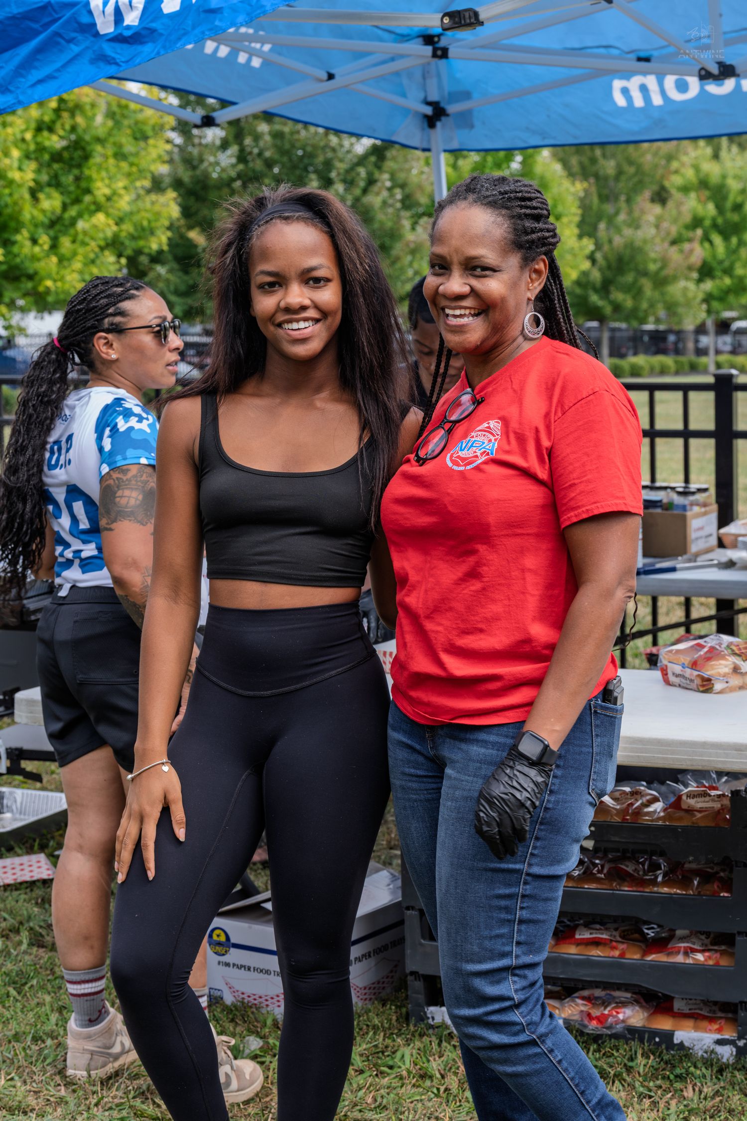 Two women smiling together at a Battle of the Badges charity softball game event.