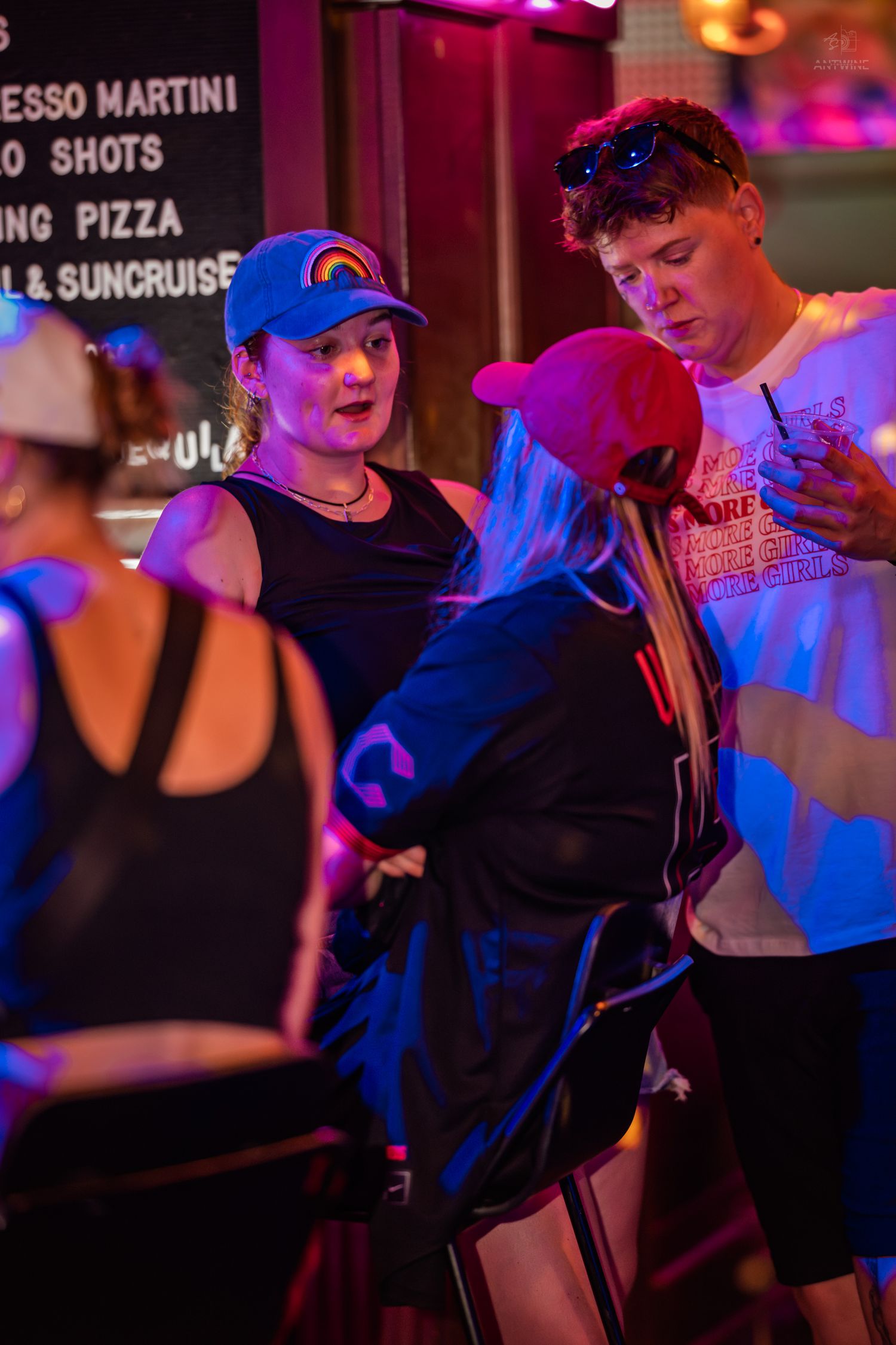 Young people socializing and dancing in a vibrant neon-lit bar at night.