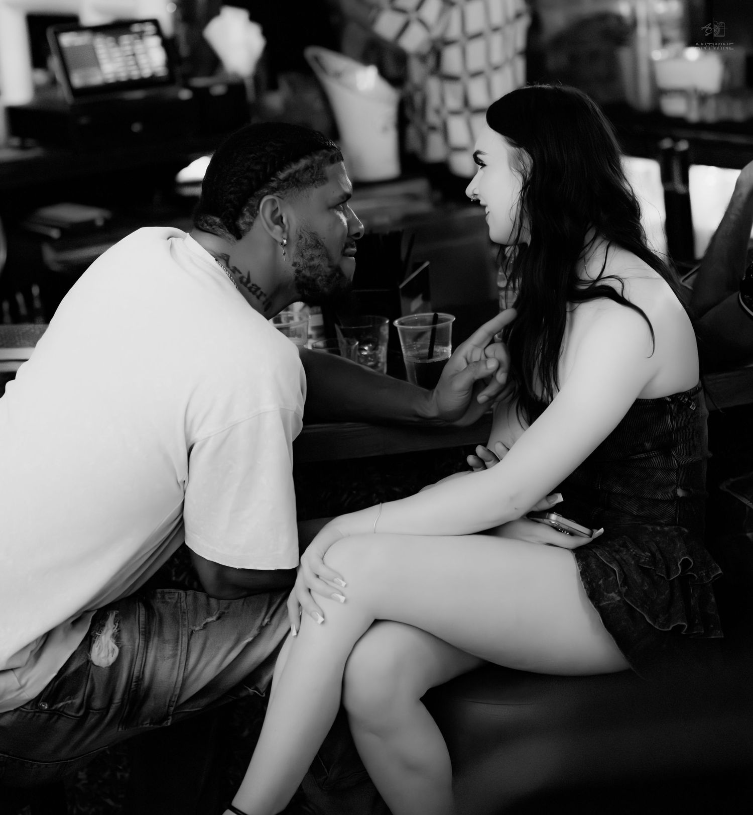 Black and white image of a couple holding hands and sharing a romantic moment at a bar.