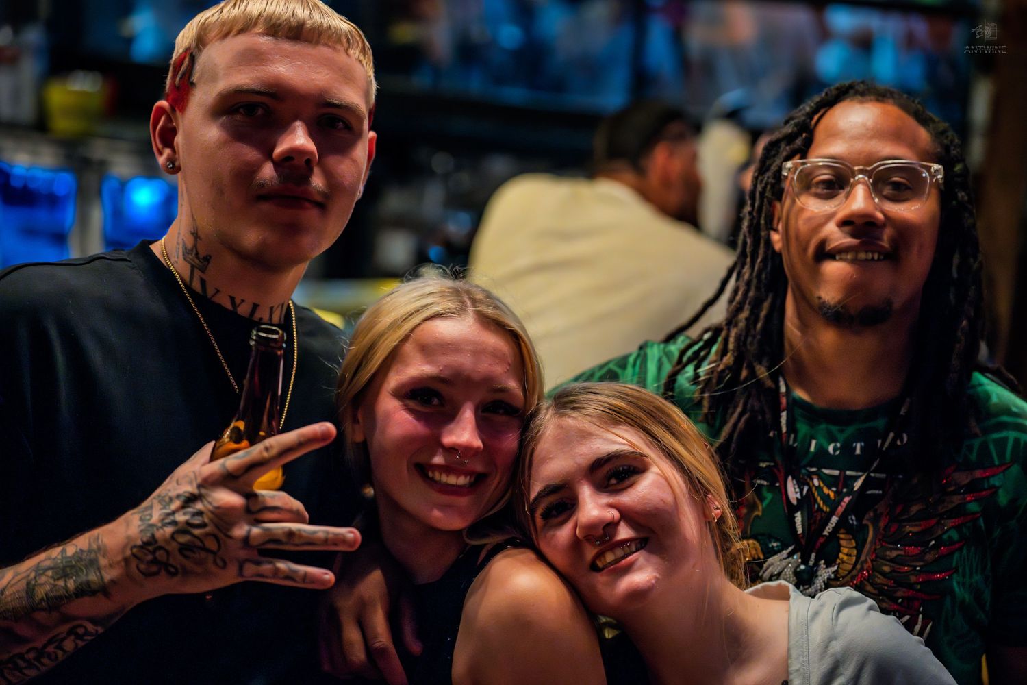 Two men and two women smiling together for a group photo at a lively bar.