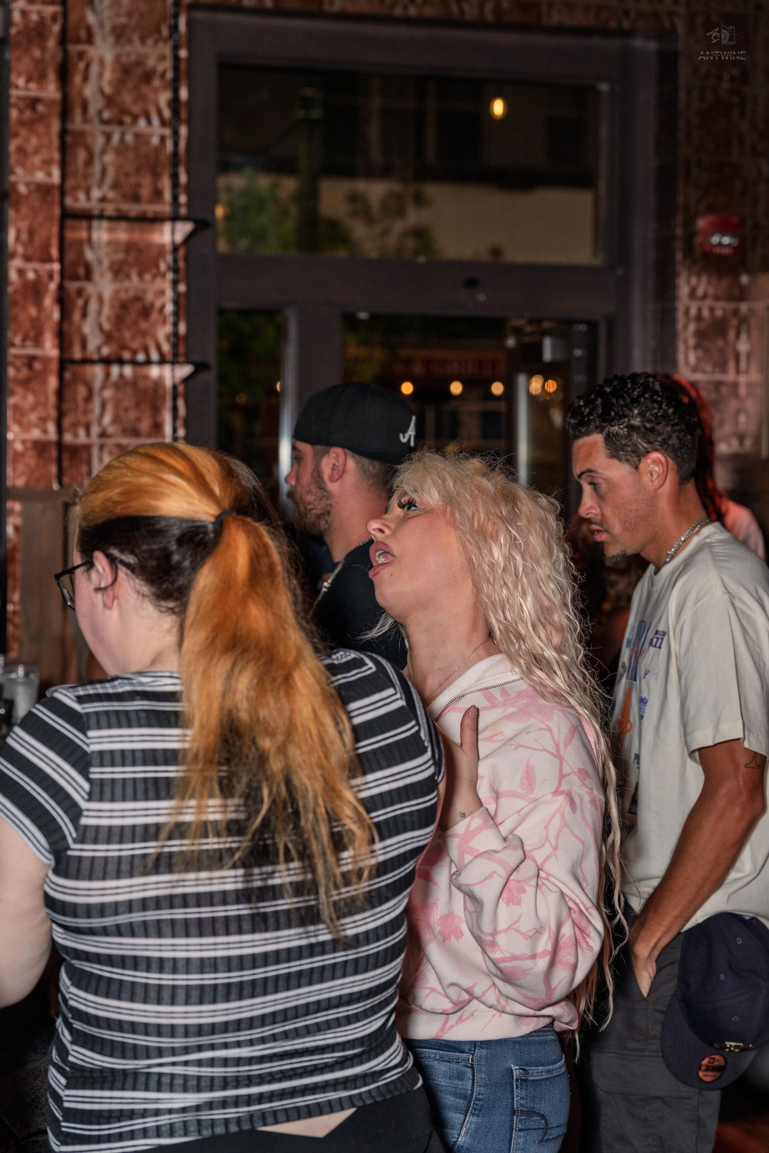 Group of people standing in line outside a bar or nightclub venue.