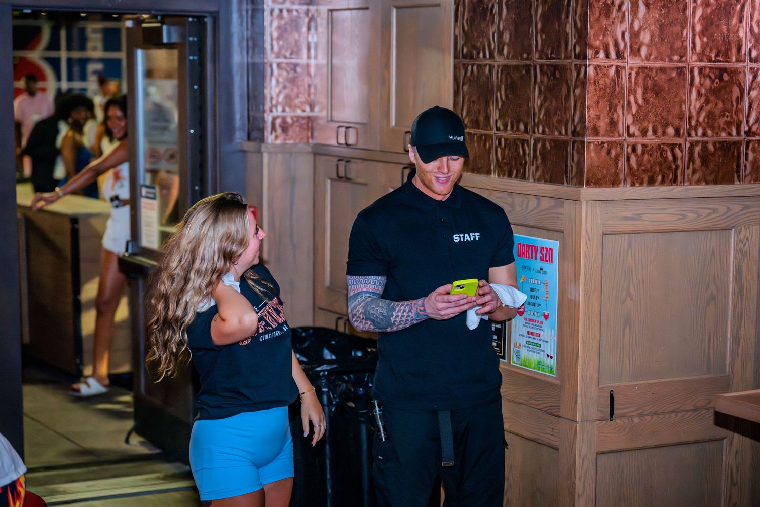 Tattooed nightclub staff member reviewing documents with a female patron.
