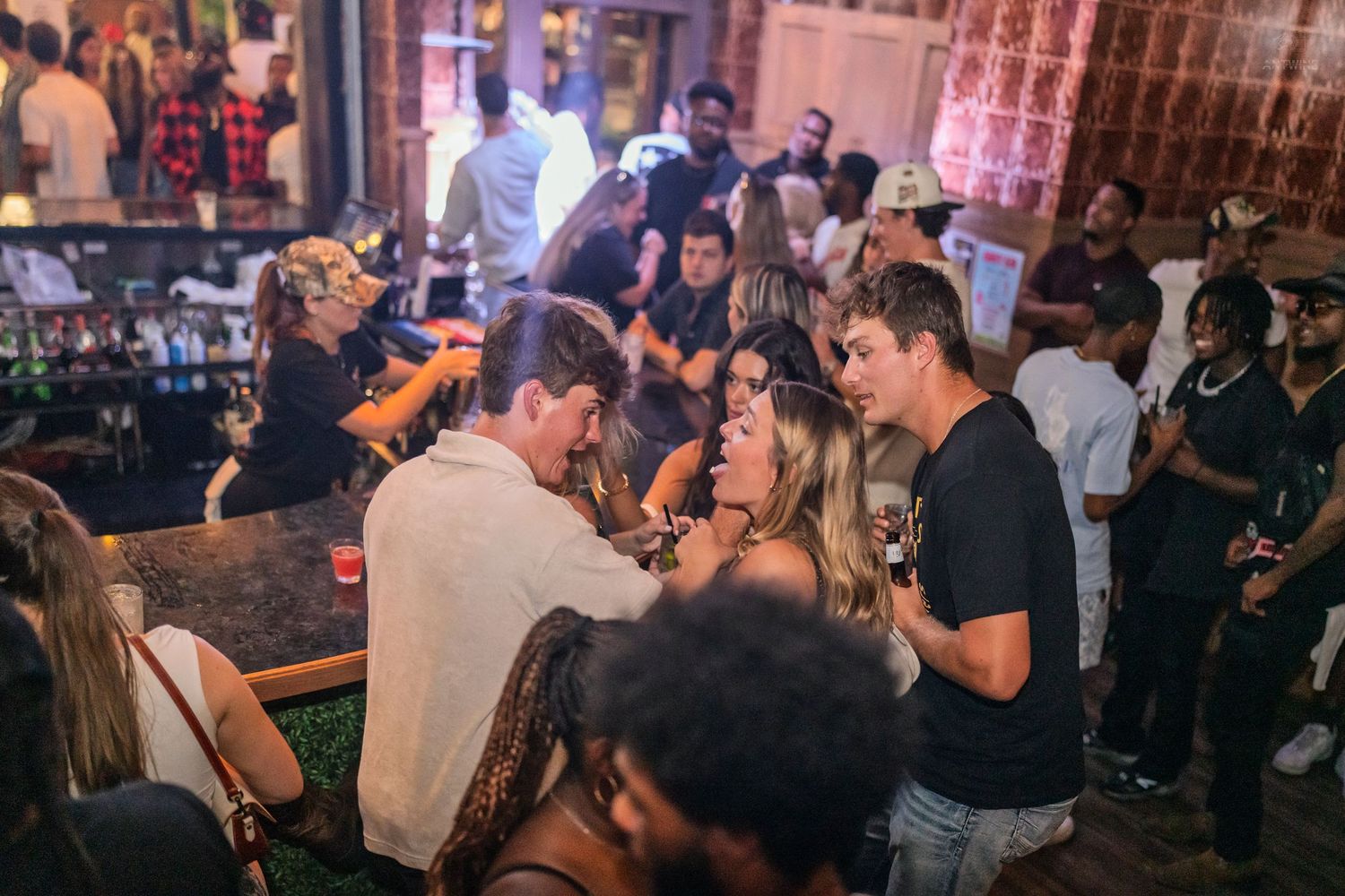 Friends laughing and chatting together at a dimly lit bar during a night out.